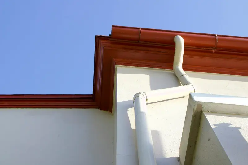 Gutter and downspout along the roof edge of a home